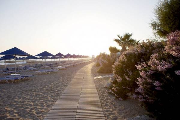 Promenade am Aquila Rithymna Beach Hotel mit Sonnenschirmen und Blumen