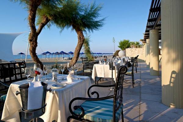 Restaurant im Freien am Strand des Aquila Rithymna Beach Hotels mit Tischen und Stühlen.