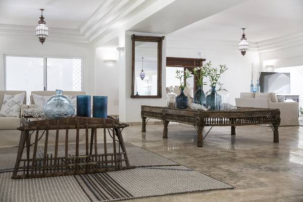 Wohnzimmer im Falkensteiner Resort Capo Boi mit zwei Sofas, Holztischen und blauen Vasen.