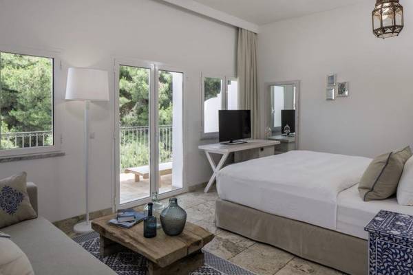 Schlafzimmer im Falkensteiner Resort Capo Boi Hotel mit großem Bett, Fenstern und Balkon