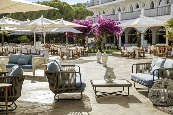 Terrasse des Falkensteiner Resorts Capo Boi mit Möbeln und Tischen unter Schirmen
