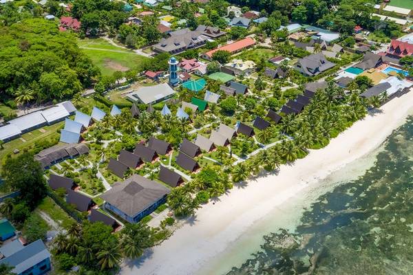 Luftaufnahme des La Digue Island Lodges an einem Strand mit vielen kleinen Hütten und grüner Vegetation.