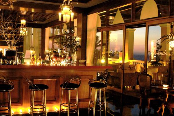 Innenansicht der Lounge Bar im Minos Imperial Beach Resort mit Barhockern und Blick auf die Terrasse.