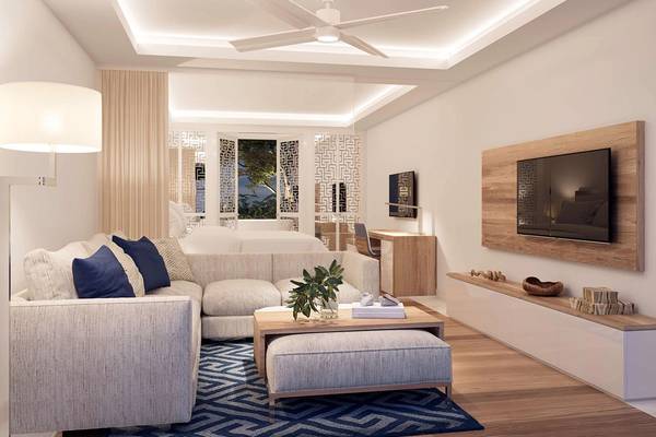 Wohnzimmer im Minos Imperial Beach Resort mit modernem Design, großer Couch, Fernseher und heller Beleuchtung.