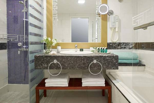 Badezimmer im Minos Imperial Beach Resort mit Marmorwaschbecken und blauen Fliesen.
