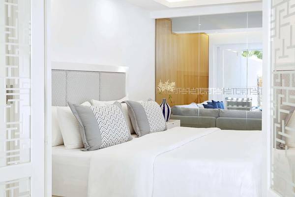 Schlafzimmer im Minos Imperial Beach Resort mit Bett, Kissen, Couch und Blumenvase.
