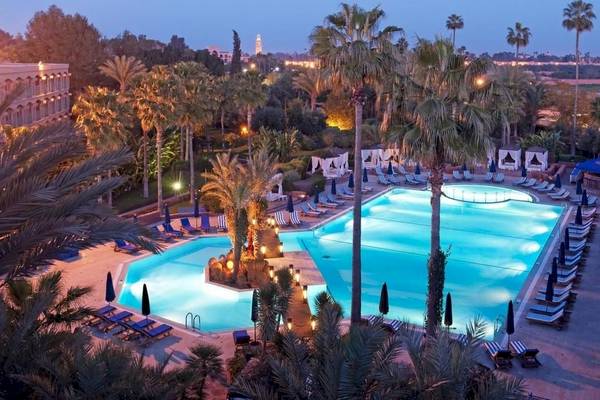 Le Meridien N'Fis Hotel Pool von oben gesehen mit Palmen und Sonnenliegen.