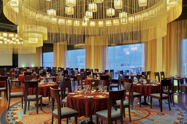 Restaurant im Hurghada Long Beach Resort mit eleganten Tischen und Stühlen, großen Kronleuchtern und Fenstern mit Stadtblick.