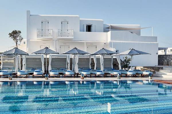 Poolbereich des Myconian Kyma Hotels mit weißen Sonnenliegen und Sonnenschirmen.