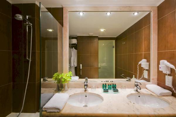 Badezimmer im Zante Park Resort & Spa, BW Premier Collection mit zwei Waschbecken, Spiegel und Handtüchern.
