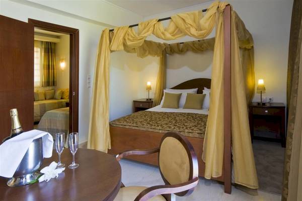 Hotelzimmer im Zante Park Resort & Spa mit Baldachin-Bett, Tisch mit Champagner und Gläsern.