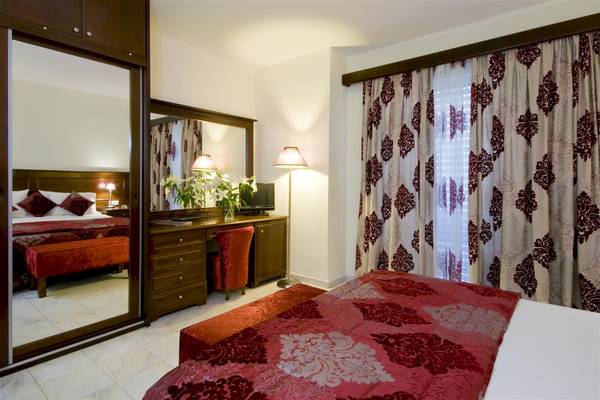 Hotelzimmer im Zante Park Resort & Spa mit Bett, Spiegel, Schreibtisch und roter Dekoration.