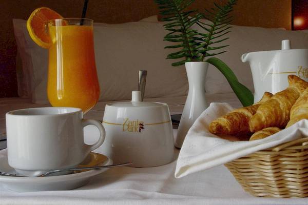 Frühstückstisch im Zante Park Resort & Spa mit Orangensaft, Croissants, Kaffeetasse und Pflanzen