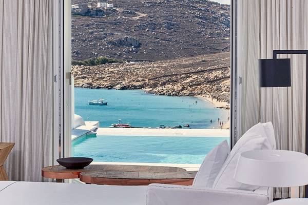 Blick aus einem Hotelzimmer des Royal Myconian Resorts auf einen Pool und das Meer.