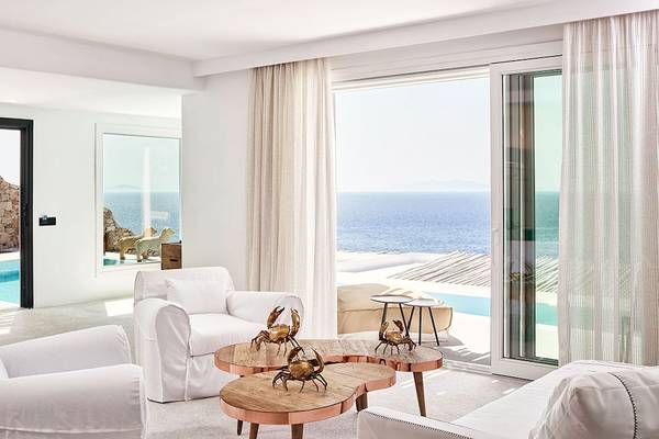 Innenraum des Royal Myconian Resorts mit Blick auf das Meer und eine Terrasse.