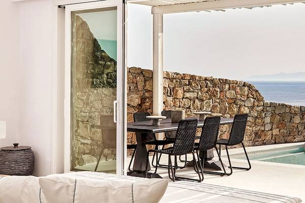 Terrasse des Royal Myconian Resorts mit Blick auf das Meer und eine Steinmauer.