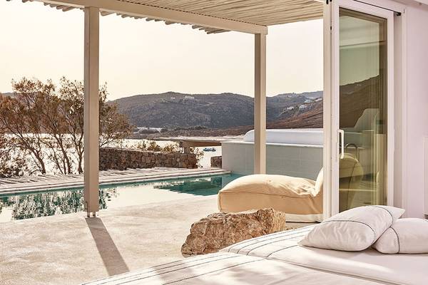 Terrasse des Royal Myconian Resorts mit Pool und Meerblick, Möbel und Lampe sind zu sehen.