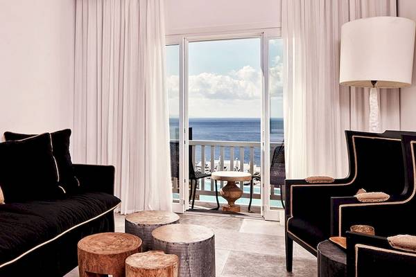 Innenbereich des Royal Myconian Resorts mit Loungebereich, Sofa, Tisch und Meerblick