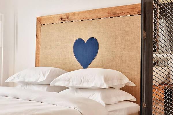 Bett im Royal Myconian Resort mit blauem Herz auf dem Kopfteil