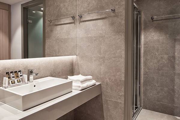 Badezimmer im Porto Bello Royal Hotel mit Waschbecken, Handtüchern und Duschbereich.