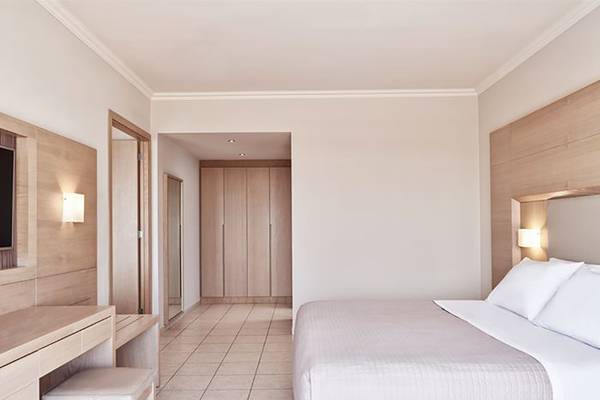 Schlafzimmer im Porto Bello Royal Hotel mit Doppelbett und modernen Holzmöbeln.