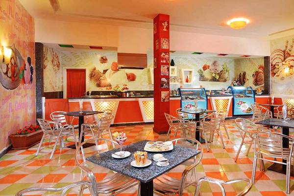 Innenbereich des Restaurants im Pickalbatros Jungle Aqua Park Resort mit bunten Fliesen, Tischen und Stühlen sowie Eiscreme-Wandmalereien.