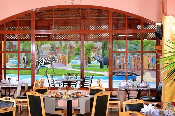 Innenansicht des Restaurants im Pickalbatros Jungle Aqua Park Resort mit Blick auf einen Swimmingpool und Tiere.