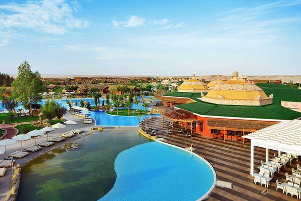 Außenansicht des Pickalbatros Jungle Aqua Park Resorts mit Swimmingpools, Sonnenliegen und grünem Dach.
