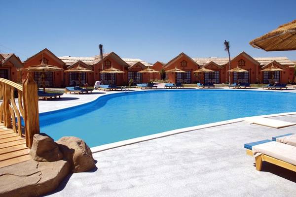 Der Swimmingpool des Pickalbatros Jungle Aqua Park Resorts mit umliegenden Sonnenliegen und Strohdächern.