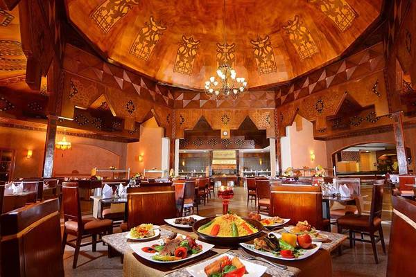 Innenansicht des Restaurants im Pickalbatros Jungle Aqua Park Resort mit runden Tischen, Holzstühlen und bunten Speisen.