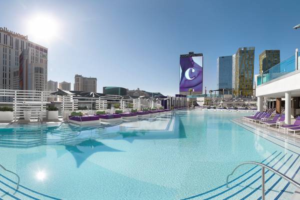 Ein Hotelpool mit Liegestühlen und Skyline im Hintergrund