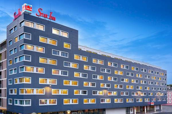 Außenansicht des Star Inn Hotel Wien Schönbrunn mit vielen Fenstern und einem großen roten Schriftzug.