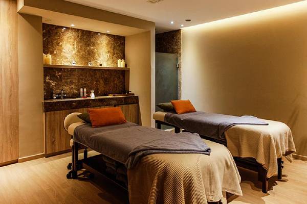 Massage-Lounge im Crystal Springs Beach Hotel mit zwei Massagebetten und Holzmöbeln.