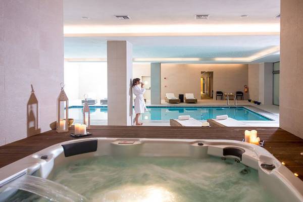 Jacuzzi im Innenbereich des Astir Odysseus Kos Resort & Spa mit einer Frau im Hintergrund.