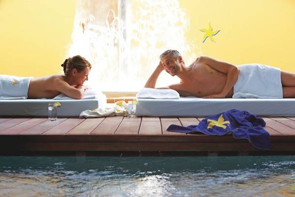 Zwei Personen genießen eine Massage im Spa-Bereich am Pool des Astir Odysseus Kos Resort & Spa.