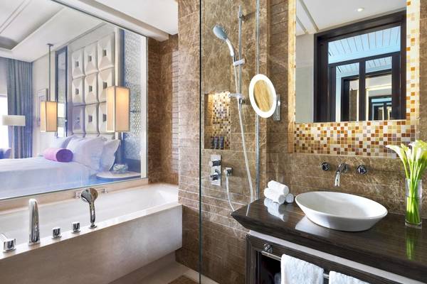 Badezimmer im Al Bustan Palace, A Ritz Carlton Hotel mit Badewanne, Dusche, Waschbecken und Fenster.
