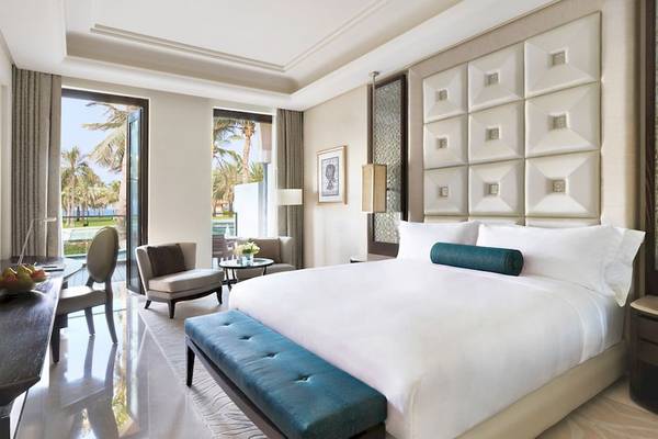 Luxuriöse Hotelsuite im Al Bustan Palace, mit Blick auf den Pool und die Palmen.