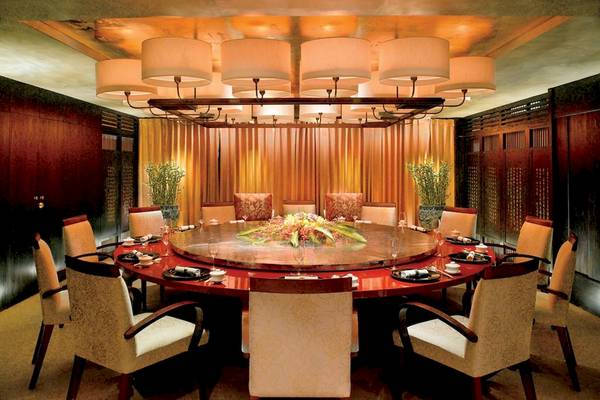 Esszimmer im Al Bustan Palace, A Ritz Carlton Hotel mit einem runden Tisch und Stühlen.