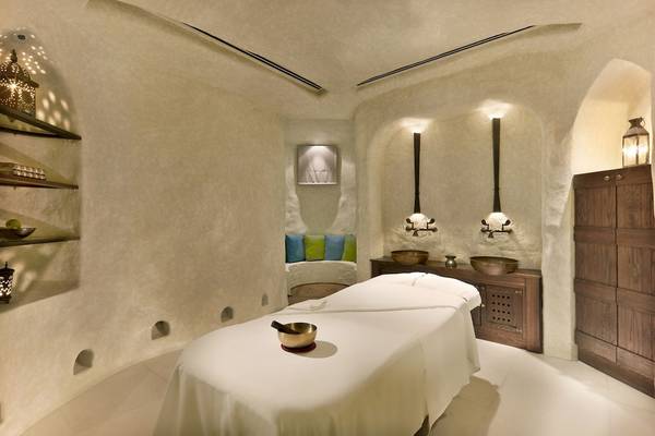 Behandlungsraum im Al Bustan Palace, A Ritz Carlton Hotel mit weißen Wänden und einer Liege.