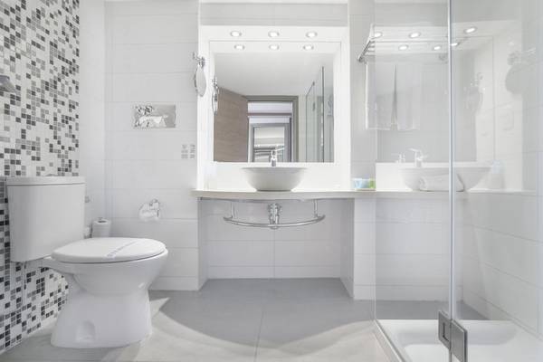Modernes Badezimmer im Vassos Nissi Plage Hotel mit weißem Design und Glasdusche.