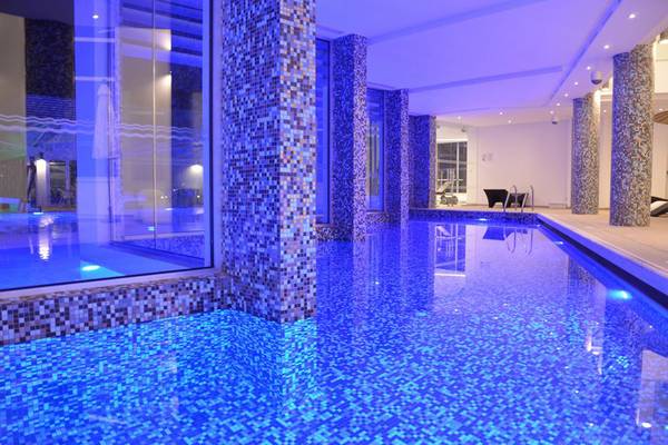 Innenpool des Vassos Nissi Plage Hotels mit blauen Lichtern und gefliesten Wänden