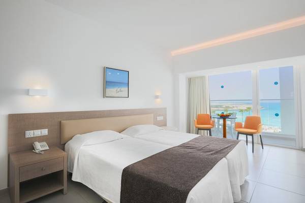 Vassos Nissi Plage Hotelzimmer mit Meerblick, zwei Betten, Tisch und Stühlen.