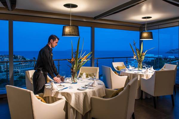 Ein Kellner bereitet einen Tisch im Blue Bay Resort Restaurant am Abend vor.