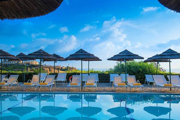 Pool-Lounge-Bereich im Blue Bay Resort mit Sonnenliegen und Strohschirmen.