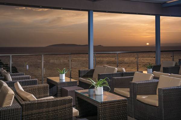 Terrasse im Blue Bay Resort mit Blick auf den Sonnenuntergang über dem Meer.