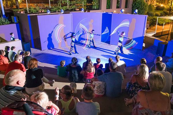 Besucher des Blue Bay Resorts beobachten eine Aufführung mit Lichteffekten auf der Bühne.