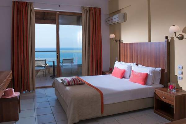 Zimmer im Blue Bay Resort mit Blick auf das Meer von einem großen Bett aus gesehen.