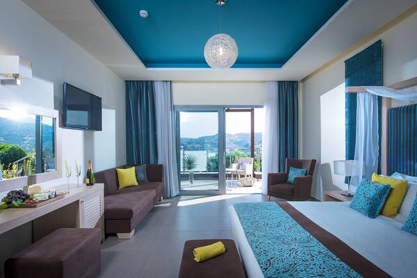 Innenansicht eines Zimmers im Blue Bay Resort mit Blick auf den Balkon und das Meer.