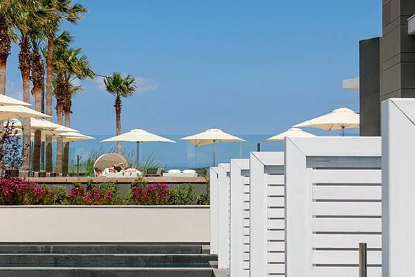 Terrasse des Aqua Blu Boutique Hotel & Spa mit weißen Sonnenschirmen und Palmen
