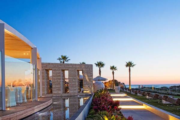 Aqua Blu Boutique Hotel & Spa Außenbereich bei Sonnenuntergang mit Glasfassade, Sitzbereich und Palmen